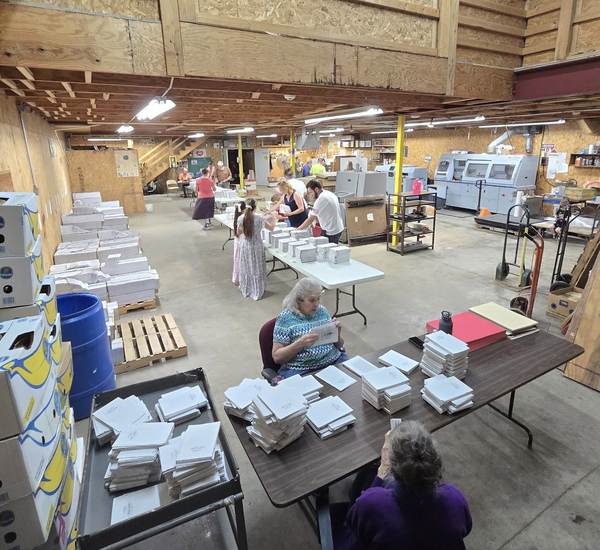 Church members collating Scripture pages at work tables